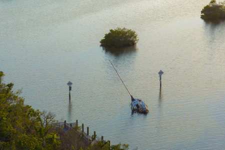 Capsized sunken sailing boat left forsaken on shallow bay waters after hurricane Ian in Manasota, Floridaの写真素材