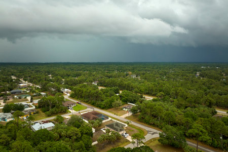Dark stormy clouds forming on gloomy sky before heavy rainfall over suburban town areaの写真素材
