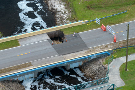 Roadworks site. Reconstruction of damaged road bridge destroyed by river after flood water washed away asphalt. Rebuilding of ruined transportation infrastructureの写真素材