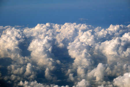 View from plane window of white rain clouds forming on blue sky. Air travel conceptの写真素材