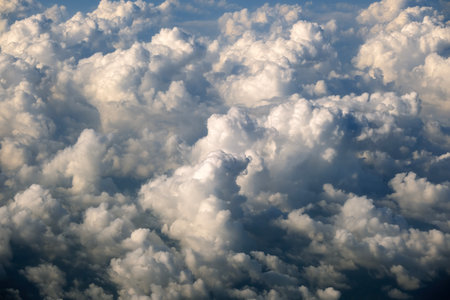 Aerial view from above at high altitude of dense puffy cumulus clouds flying. Amazing from airplane window point of viewの写真素材