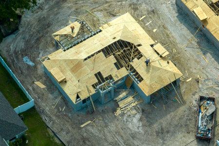 Aerial view of builders working on unfinished residential house with wooden roof frame structure under construction in Florida suburban areaの写真素材