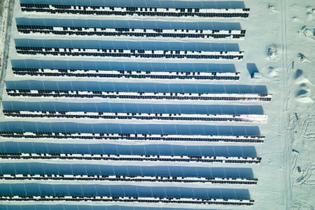 Aerial view of electrical power plant with solar panels covered with snow melting down in winter end for producing clean energy. Concept of low effectivity of renewable electricity in northern regionの写真素材