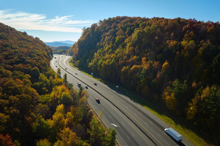 Aerial view of I-40 freeway in North Carolina leading to Asheville through Appalachian mountains in golden fall with fast moving trucks and cars. Interstate transportation conceptの写真素材