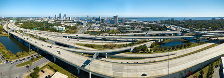 Aerial view of Jacksonville city with high office buildings and american freeway intersection with fast driving cars and trucks. View from above of USA transportation infrastructureの写真素材