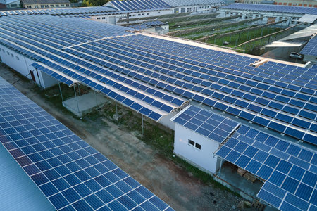 Aerial view of solar power plant with blue photovoltaic panels mounted on industrial building roof for producing green ecological electricity. Production of sustainable energy conceptの写真素材