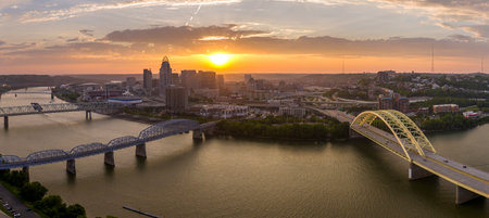 Cincinnati, Ohio with driving cars on Daniel Carter Beard Bridge highway near illuminated skyscraper buildings in downtown district in USA. American city with business financial district at sunsetの写真素材