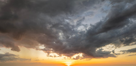 Colorful sunset sky with setting sun behind vivid orange and yellow cloudsの写真素材