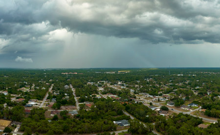 Dark stormy clouds forming on gloomy sky before heavy rainfall over suburban town areaの写真素材