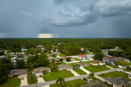 Dark stormy clouds forming on gloomy sky during heavy rainfall season over suburban town areaの写真素材