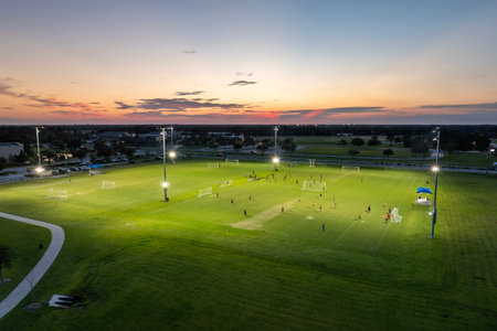 Sportsmen playing football game on illuminated stadium in public sports parkの写真素材