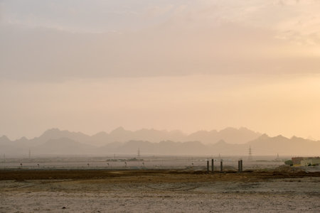 Sunset landscape with dark mountain peaks in egyptian desert and high voltage power linesの写真素材