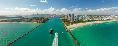Aerial view of container ship entering in Miami harbor main channel near South Beach. Luxurious hotels and apartment buildings on waterfront and high skyscrapers of downtown district in distanceの写真素材