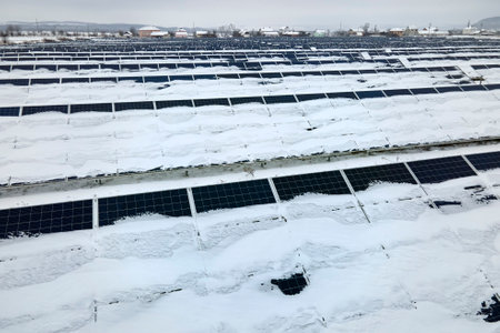 Aerial view of snow covered sustainable electric power plant with rows of solar photovoltaic panels for producing clean electrical energy. Low effectivity of renewable electricity in northern winterの写真素材
