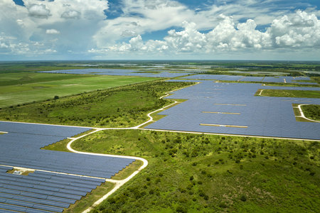 Aerial view of sustainable electric power plant between agricultural farm fields with solar photovoltaic panels for producing clean electrical energy. Renewable electricity with zero emission conceptの写真素材