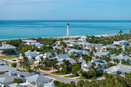 Boca Grande, Florida. Lighthouse on ocean shore for commercial vessels navigation. Waterfront houses between green palm trees on Gasparilla Islandの写真素材