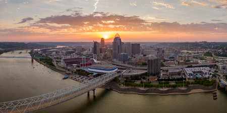 Highway traffic on bridge in Cincinnati, Ohio with brightly illuminated high skyscraper buildings in downtown district. American city with business financial district at sunsetの写真素材