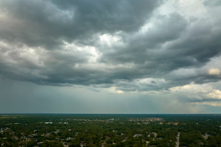 Landscape of dark ominous clouds forming on stormy sky before heavy thunderstorm over rural town areaの写真素材