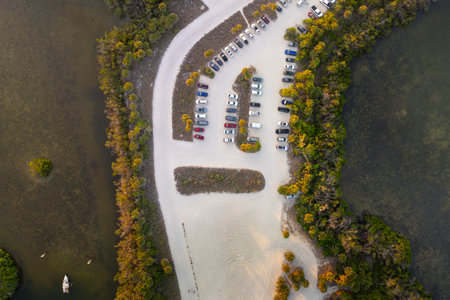 Parking lot for tourists cars in front of ocean beach with soft white sand in Florida. Popular vacation spot at sunsetの写真素材