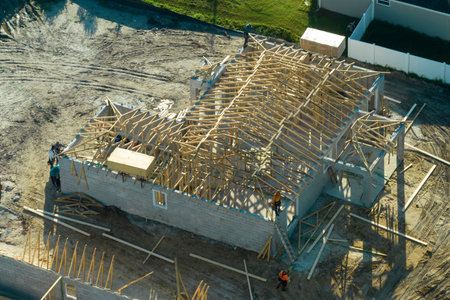 Professional builders working on roof construction of unfinished suburban home with wooden frame structure in Florida rural area. Concept of housing development in Americaの写真素材