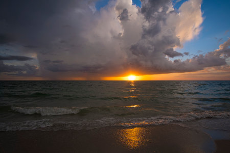 Sunset landscape of dark ominous rainstorm with lightning and thunder over sea water waves. Beautiful seascape in eveningの写真素材