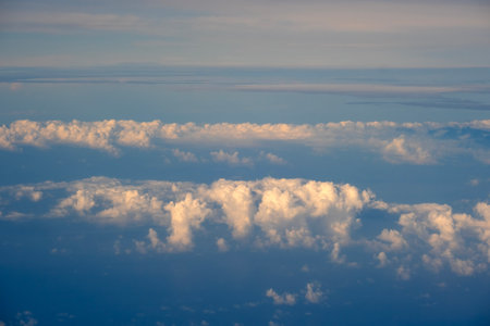 Cloudy sky, from airplane window point of view. View from above at high altitude of dense puffy...