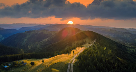 Offroad path crossing hill top. Dark dirt road illuminated with bright setting sun. Amazing sunset...