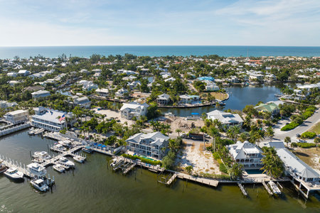 Expensive mansions between green palm trees on Gulf of Mexico shore in island small town Boca Grande on Gasparilla Island in southwest Florida, USA. Aerial view of wealthy waterfront neighborhoodの写真素材