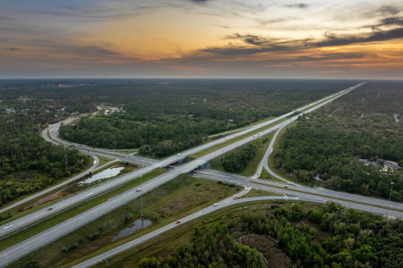 Freeway overpass junction in Florida with fast moving traffic cars and trucks in American rural area at sunset. Interstate transportation infrastructure in USAの写真素材