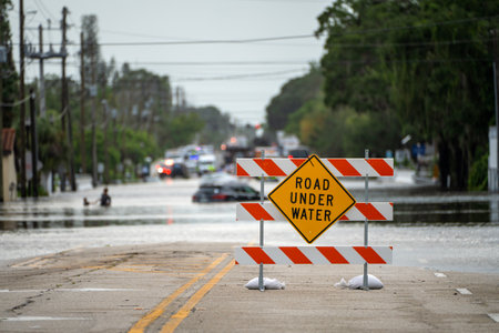 Flooded street in Florida after hurricane rainfall with road closed signs blocking driving of cars. Safety of transportation during natural disaster conceptの写真素材