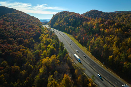 I-40 freeway road leading to Asheville in North Carolina over Appalachian mountain pass with yellow fall forest and fast moving trucks and cars. Concept of high speed interstate transportationの写真素材