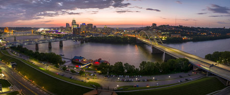 Highway traffic with driving cars on bridge in downtown district of Cincinnati city in Ohio, USA. American city skyline with brightly illuminated high commercial buildings at nightの写真素材