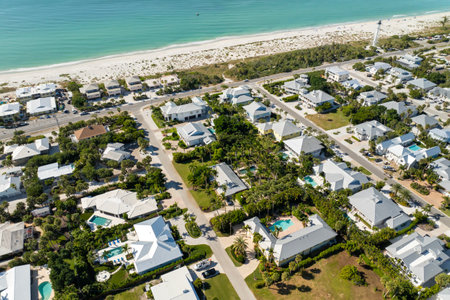 Expensive mansions between green palm trees on Gulf of Mexico shore in island small town Boca Grande on Gasparilla Island in southwest Florida, USA. Aerial view of wealthy waterfront neighborhoodの写真素材