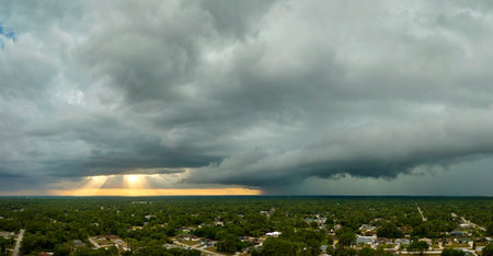Landscape of dark ominous clouds forming on stormy sky before heavy thunderstorm over rural town areaの写真素材