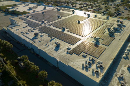Solar power plant with blue photovoltaic panels mounted on commercial shopping store building roof for producing green ecological electricity. Production of sustainable energy conceptの写真素材