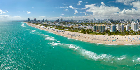 Travel destination in United States. South Beach sandy surface with tourists relaxing on hot Florida sun. Tourism infrastructure in southern USA. Miami Beach city with high luxury hotels and condosの写真素材