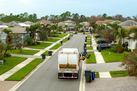 Trash truck picking up garbage bins on Florida city street curbsideの写真素材