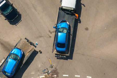 Tow truck hauling smashed vehicle on car accident site. Emergency services responding to traffic crash on American street. First responders helping on road in the USAの写真素材