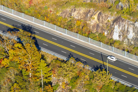 Freeway road with fast moving traffic cars and trucks in American rural area in fall season. Interstate transportation infrastructure in USAの写真素材