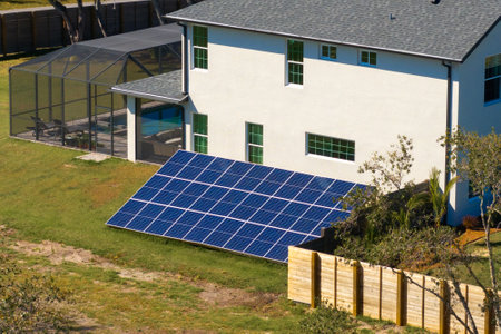 Residential house with solar photovoltaic panels for producing of clean ecological electrical energy mounted on backyard ground in suburban rural area. Concept of autonomous homeの写真素材