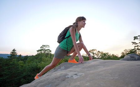 Sportive woman climbing alone on hillside rocky trail. Female hiker overcoming difficult cliff on wilderness path. Active lifestyle conceptの写真素材