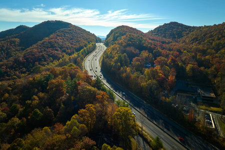 View from above of I-40 freeway route in North Carolina leading to Asheville thru Appalachian mountains with yellow fall woods and fast moving trucks and cars. Interstate transportation conceptの写真素材