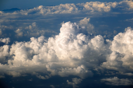 View from plane window of white rain clouds forming on blue sky.の写真素材
