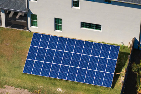 Autonomous house with solar photovoltaic panels mounted on stand-alone frame on backyard ground for...