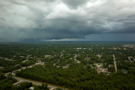 Dark stormy clouds forming on gloomy sky before heavy rainfall over suburban town areaの写真素材