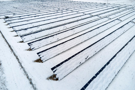Aerial view of sustainable electrical power plant with solar photovoltaic panels covered with snow...