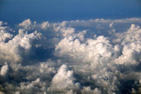 Cloudy sky, from airplane window point of view. View from above at high altitude of dense puffy cumulus cloudsの写真素材
