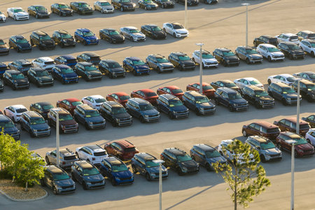Large parking lot of local dealer with many brand new cars parked for sale. Development of american...