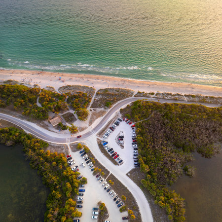 Parking lot at Blind Pass beach on Manasota Key in Englewood. Tourists cars in front of ocean beach with soft white sand in Florida. Popular vacation spot at sunsetの写真素材