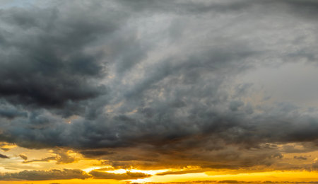 Sunset sky with bright colorful orange and yellow clouds. Panoramic skyscape